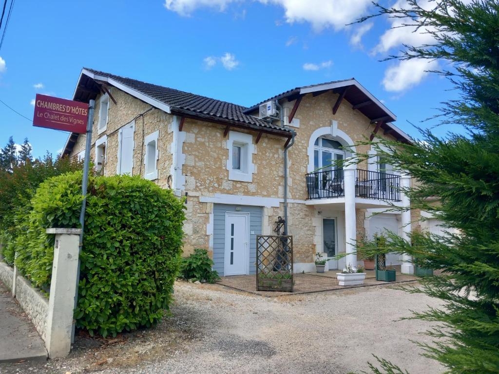 une maison en briques avec un panneau devant elle dans l'établissement Gite Le Chalet, à Saint-Laurent-des-Vignes