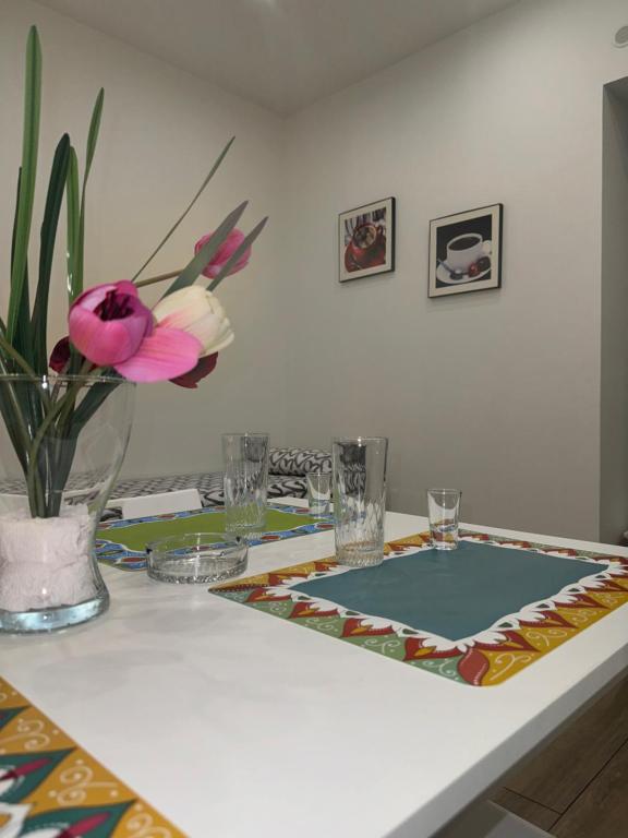 a table with a vase with a pink flower on it at Il Tulipano house in Catania