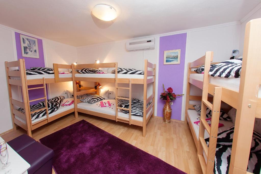 a room with three bunk beds with purple walls at Hostel Mirror in Mostar