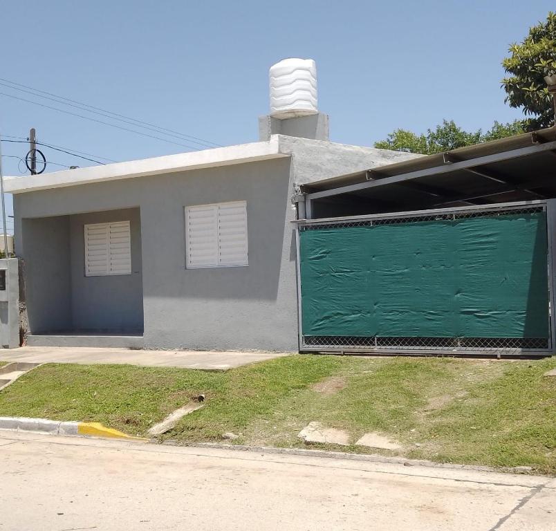 a house with a green garage door in front of it at Departamento CR in Alta Gracia
