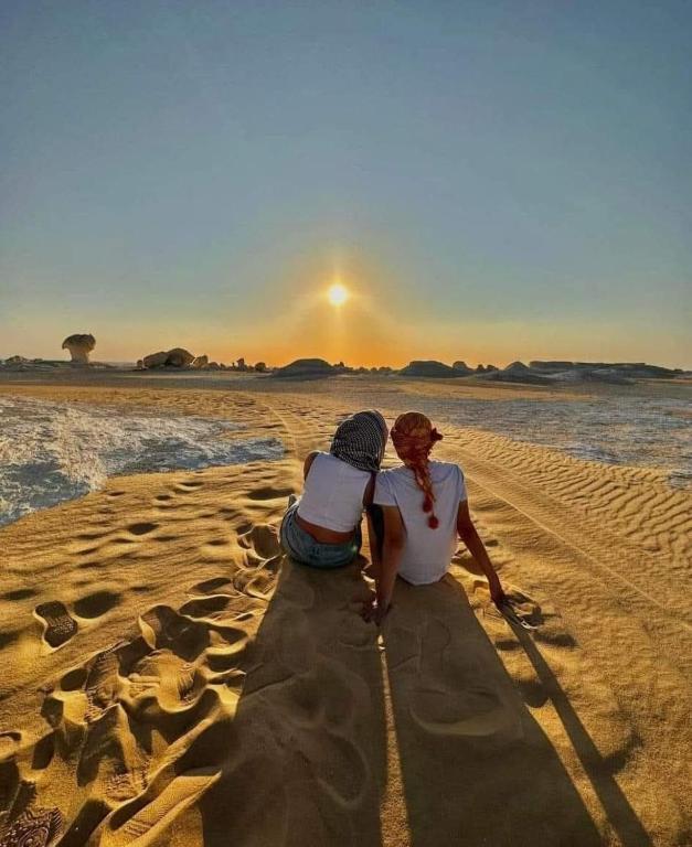 Az Zabūwhite desert camping的坐在海滩上的女人和孩子