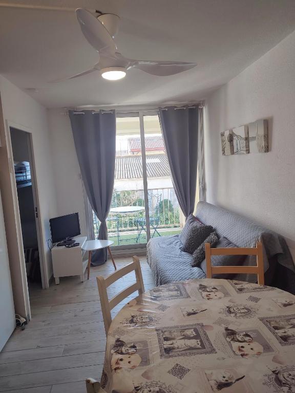 - un salon avec une table et un ventilateur de plafond dans l'établissement Appartement T2 en bord de mer - Les Capounades, à Narbonne-Plage