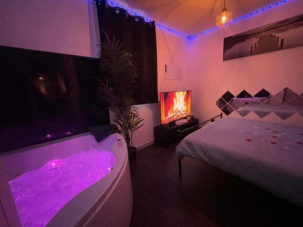 a bedroom with a bed and a tub with purple lights at Love room Buenas noches SPA et bord de mer in La Seyne-sur-Mer
