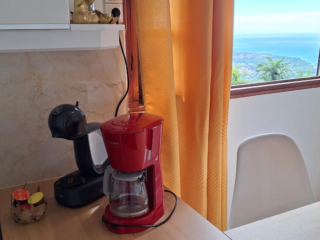 a red blender sitting on a counter next to a window at Bélavue & SPA Privé, avec vue panoramique sur mer, jardin créole paysager, jacuzzi privé in Bouillante