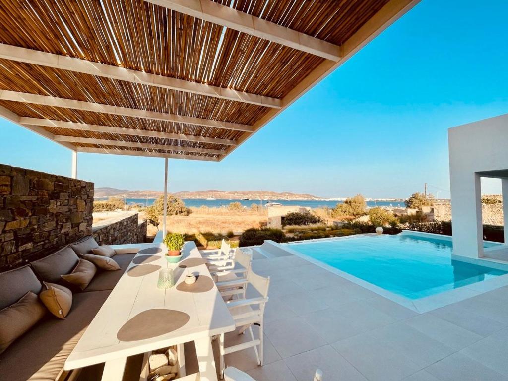 a patio with a table and chairs and a swimming pool at Dreamy Sunset Villa a few steps from the Beach in Pounda