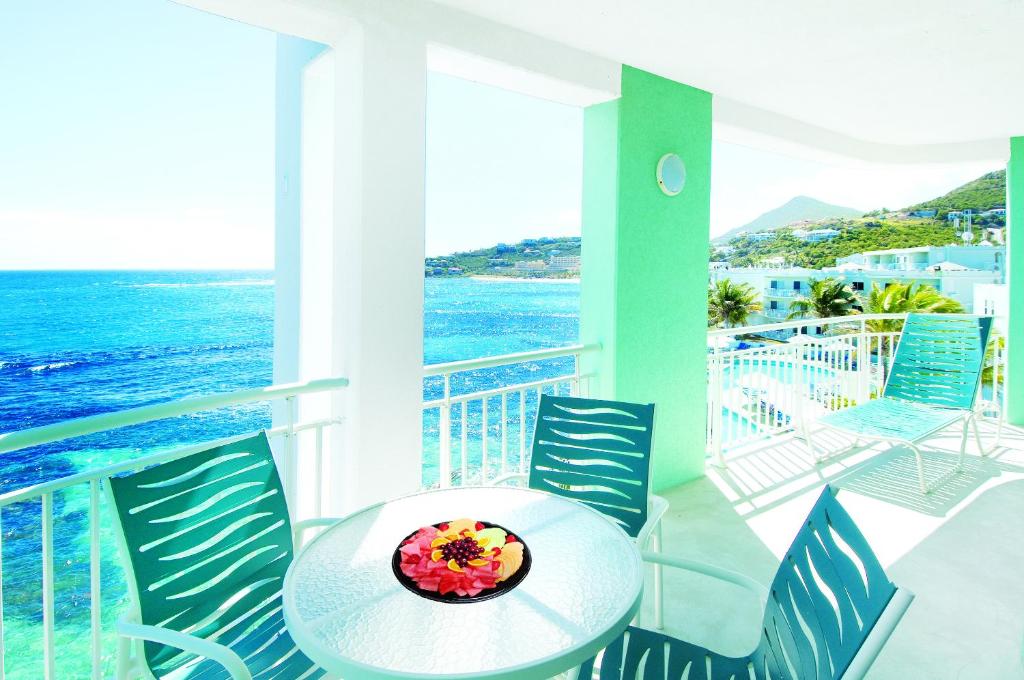 a balcony with a table and chairs and the ocean at Oyster Bay Beach Resort in Dawn Beach