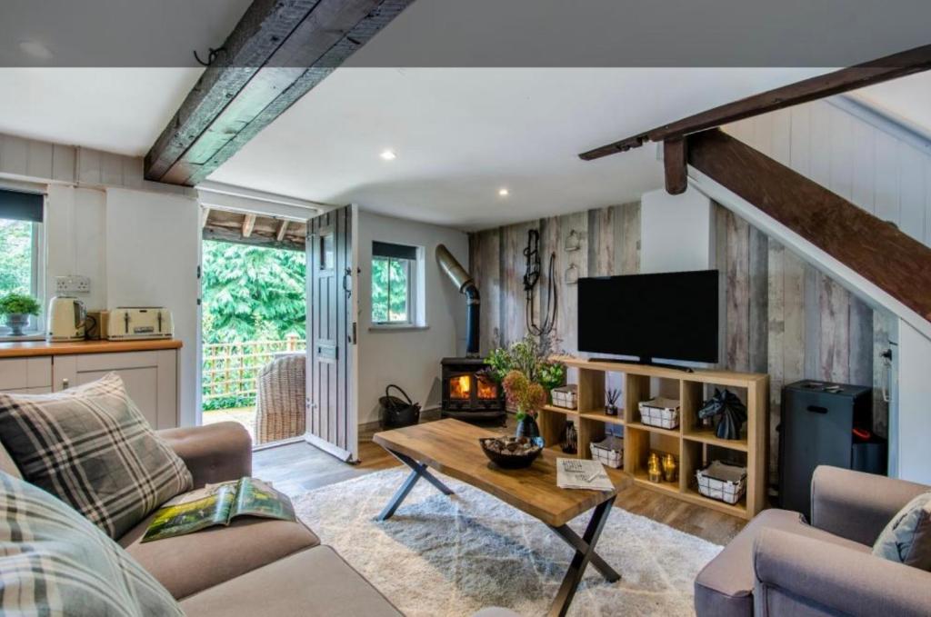 a living room with a couch and a tv at Stable boys cottage in Sedgeberrow