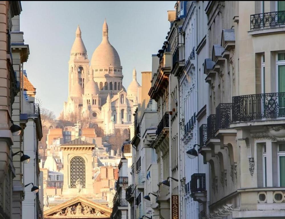 une vue de la cathédrale depuis une rue entre les bâtiments dans l'établissement Chic & Cosy - Montmartre - Cœur de Paris, à Paris