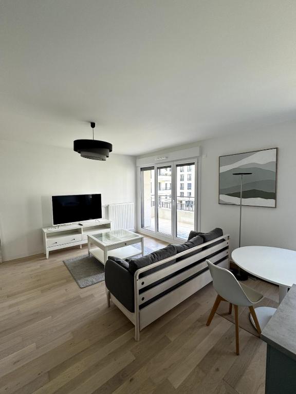 un salon avec un canapé et une table dans l'établissement Appartement calme et lumineux avec 2 chambres et un parking, à Saint-Ouen