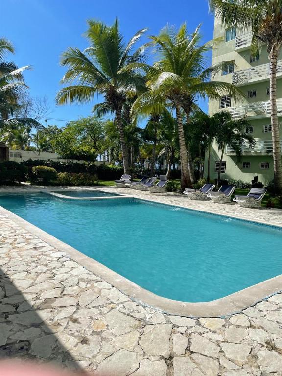 Una piscina con palmeras y un edificio. en Gran Apartamento frente al mar, en La Francia