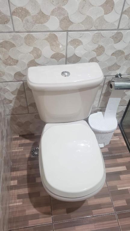 a white toilet in a bathroom with a tile wall at Chale bela vista paraisopolis mg in Paraisópolis