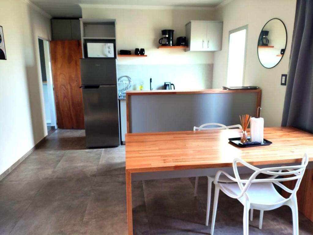 eine Küche mit einem Holztisch und weißen Stühlen in der Unterkunft PH SomoS in San José