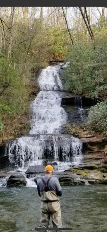 a man standing in the water in front of a waterfall at Twin Oaks in Bryson City