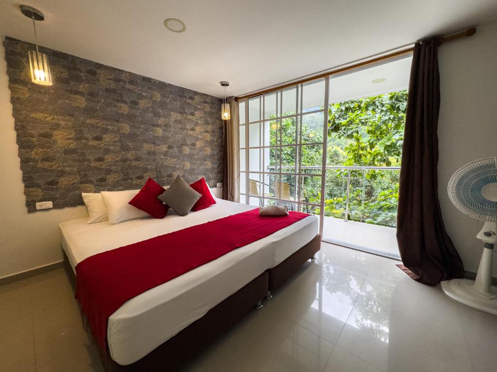 a bedroom with a large bed and a large window at Montes De Beraka in Minca