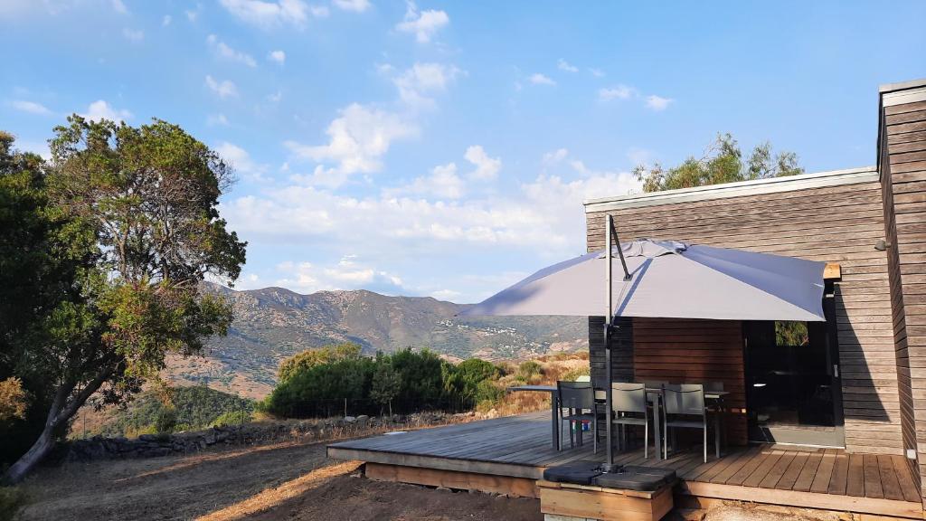 une terrasse en bois avec une table et un parasol dans l'établissement Havre de paix à 10 minutes de la mer et 15 minutes d'Ajaccio, à Appietto