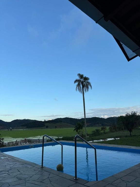 a swimming pool with a palm tree in the background at Casa de campo em Gaspar in Gaspar