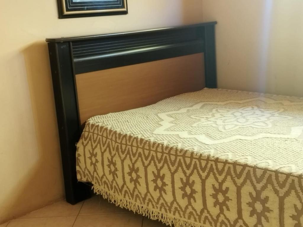 a bed with a wooden headboard in a room at Casa Lilytemporada in Cabo Frio