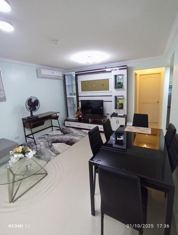 a living room with a dining table and a television at 2 Bedroom Condo Unit Cebu Spacious and Convenient in Cebu City