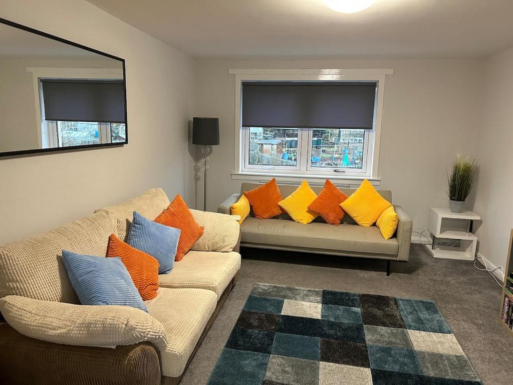 グリーノックにあるSpacious two bedroom apartment, entire placeのリビングルーム(カラフルな枕とソファ2台付)