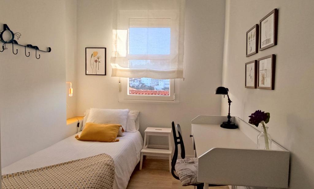 a bedroom with a bed and a desk and a window at Apartamento Arcoiris in Betanzos