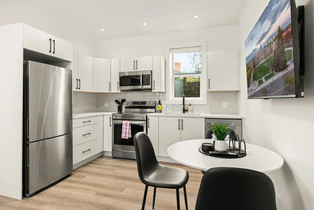 a kitchen with a table and chairs and a refrigerator at Cozy Saanich Cottage ideal location to UVIC and Downtown in Victoria