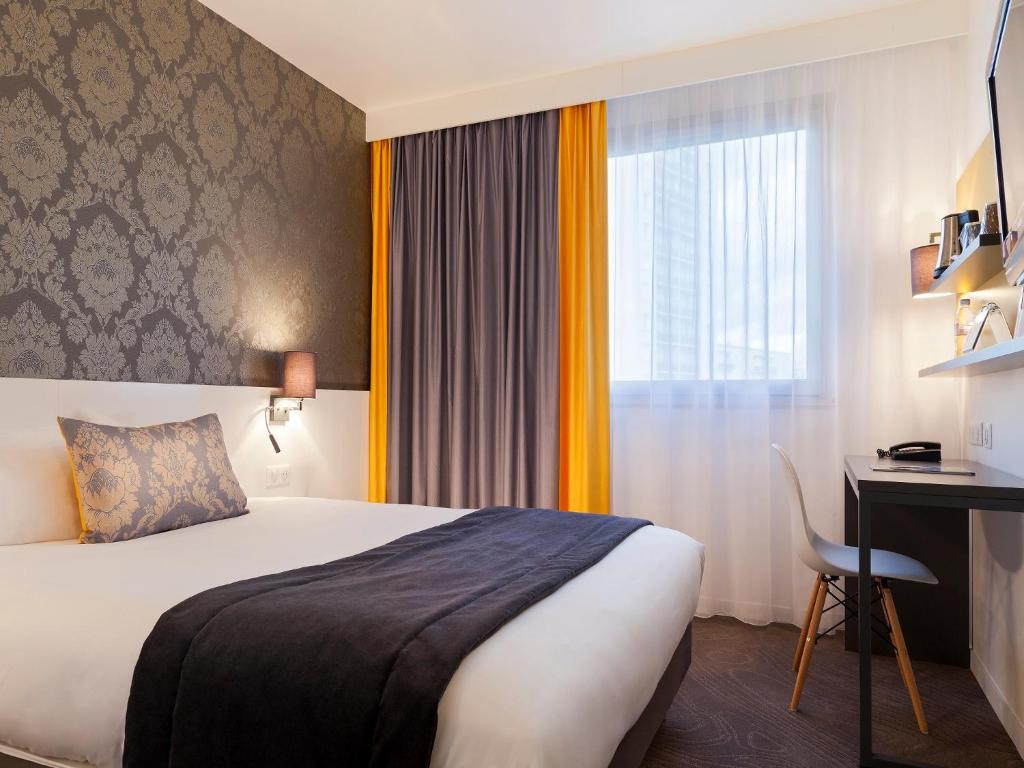 ein Hotelzimmer mit einem Bett, einem Schreibtisch und einem Fenster in der Unterkunft Hotel Kyriad Tours St Pierre des Corps Gare in Saint-Pierre-des-Corps