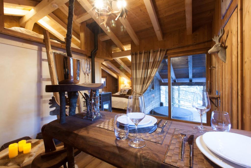 a dining room with a table with wine glasses on it at Cabane entre terre et ciel in Saint-Nicolas-la-Chapelle