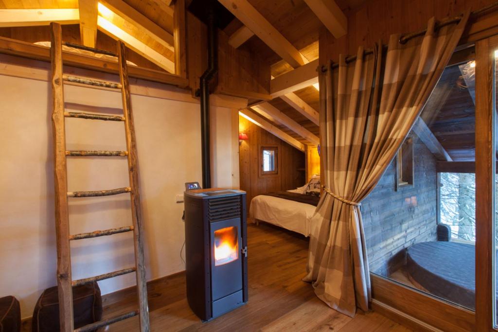a room with a fireplace and a bedroom with bunk beds at Cabane entre terre et ciel in Saint-Nicolas-la-Chapelle