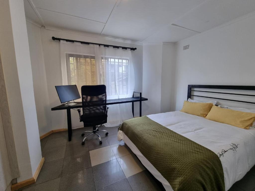 a bedroom with a bed and a desk with a computer at Sandalwood Property in Lusaka