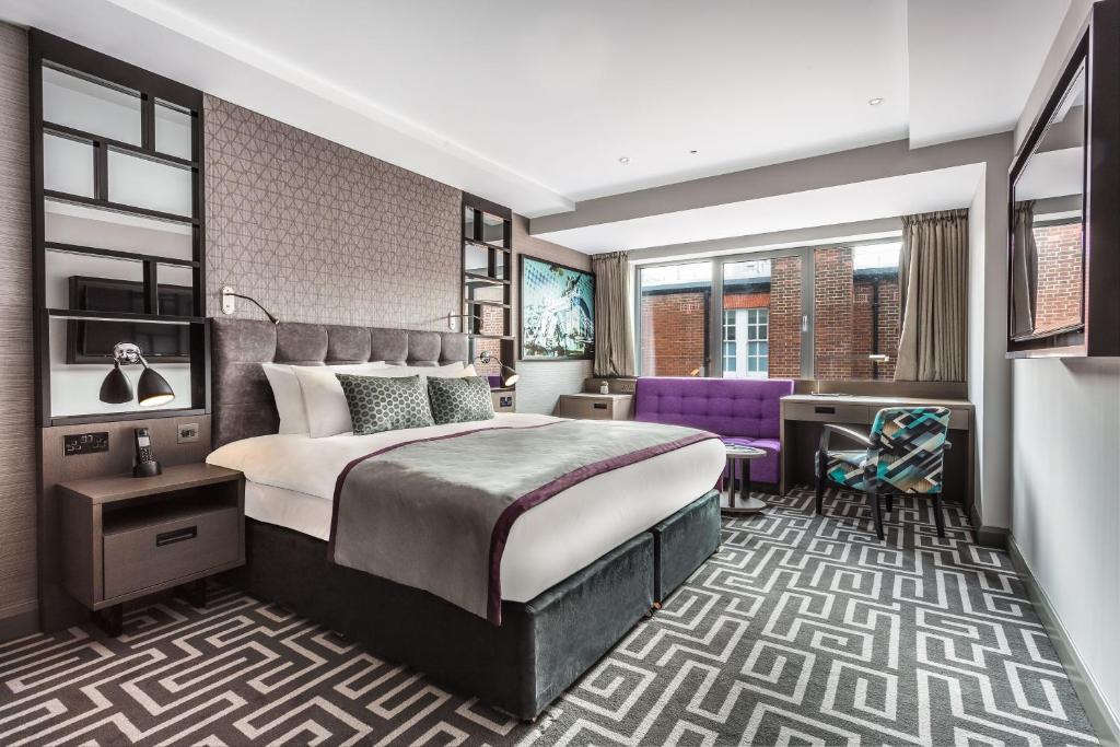 ロンドンにあるコー​​トハウス ホテル ショアディッチの大きなベッドと紫色の椅子が備わるホテルルームです。