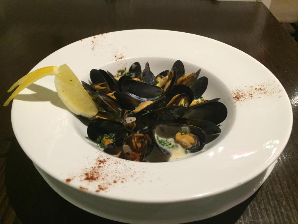 a bowl of mussels with a lemon on a table at Hatton's of Garadice in Garadice