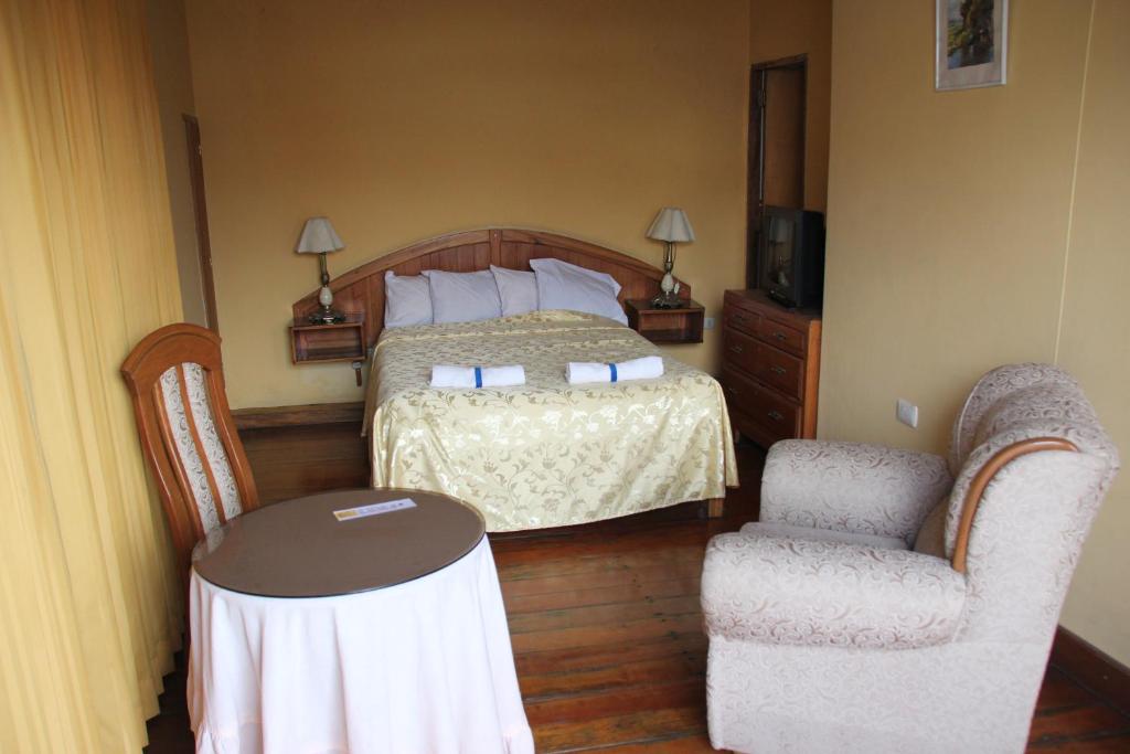 1 dormitorio con 1 cama, 2 sillas y mesa en Hostal Lluvia de Oro, en Arequipa