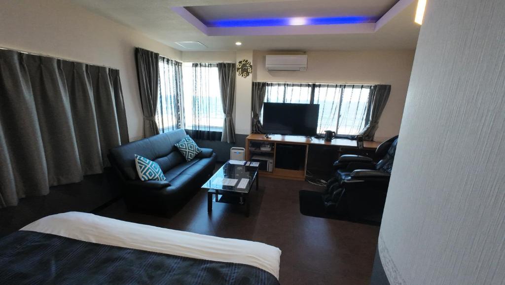 a living room with a couch and a tv in a hotel room at ブルーエール in Nobeoka