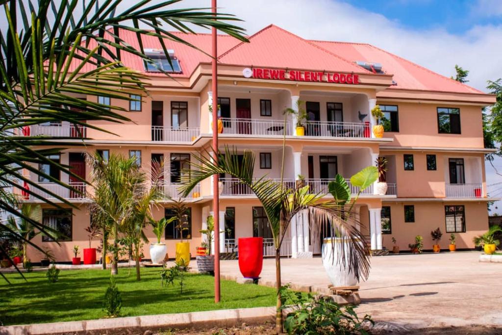 a large pink building with palm trees in front of it at Irewe Silent Lodge in Arusha