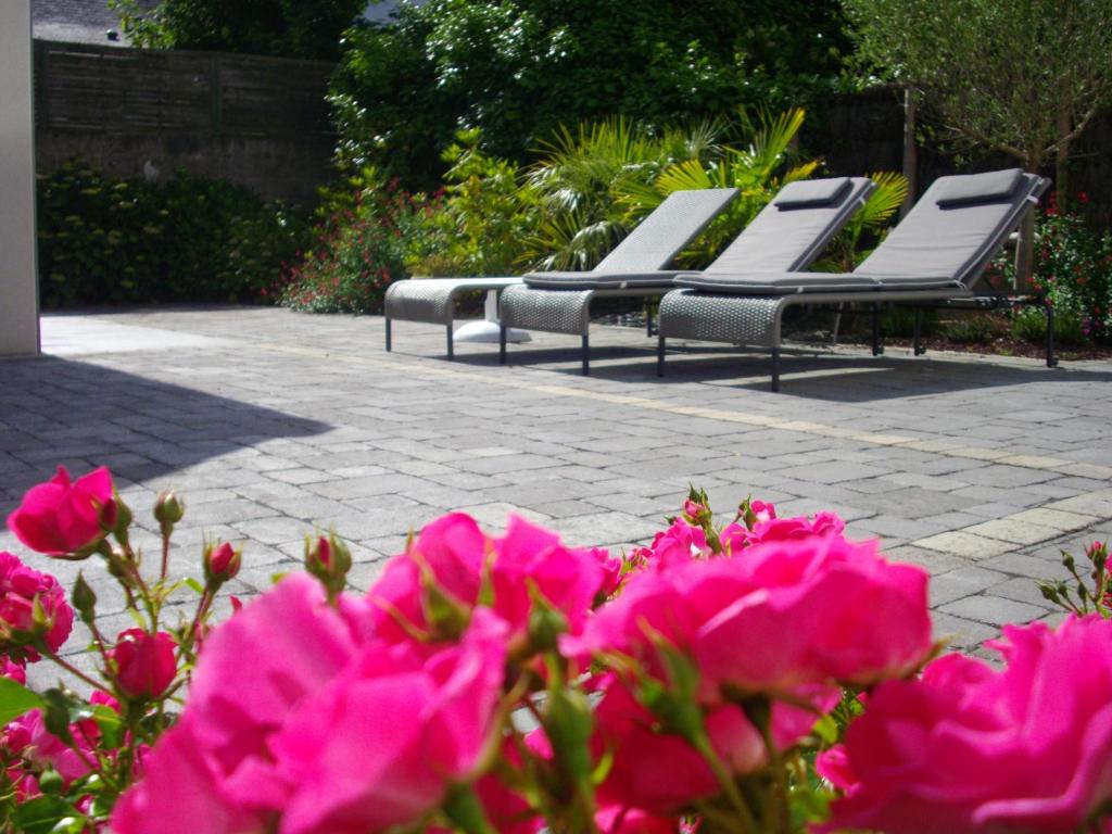 a group of chairs sitting on a patio with pink flowers at Hotel Mona Lisa in La Baule