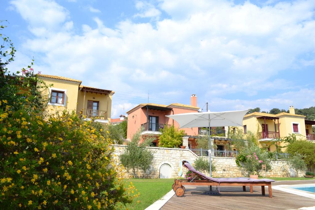 a patio with a bench and an umbrella in front of a house at Alkyon Villas in Syvota