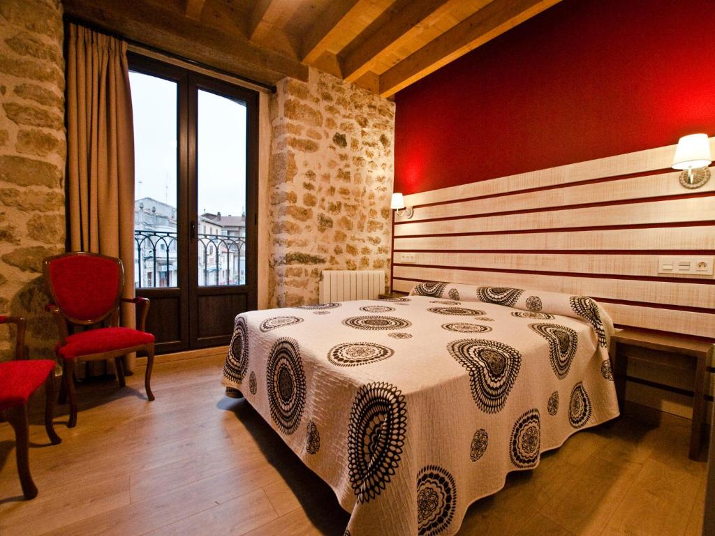 La Casa de Beli في Tardajos: غرفة نوم بسرير وجدار احمر