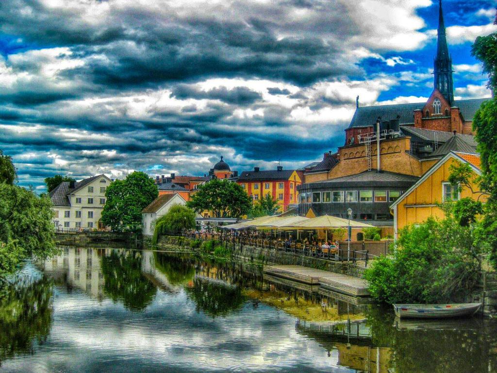 a city with a river with buildings and a church at Modern & New Apartment Near CenterUniHospital With Balcony in Uppsala