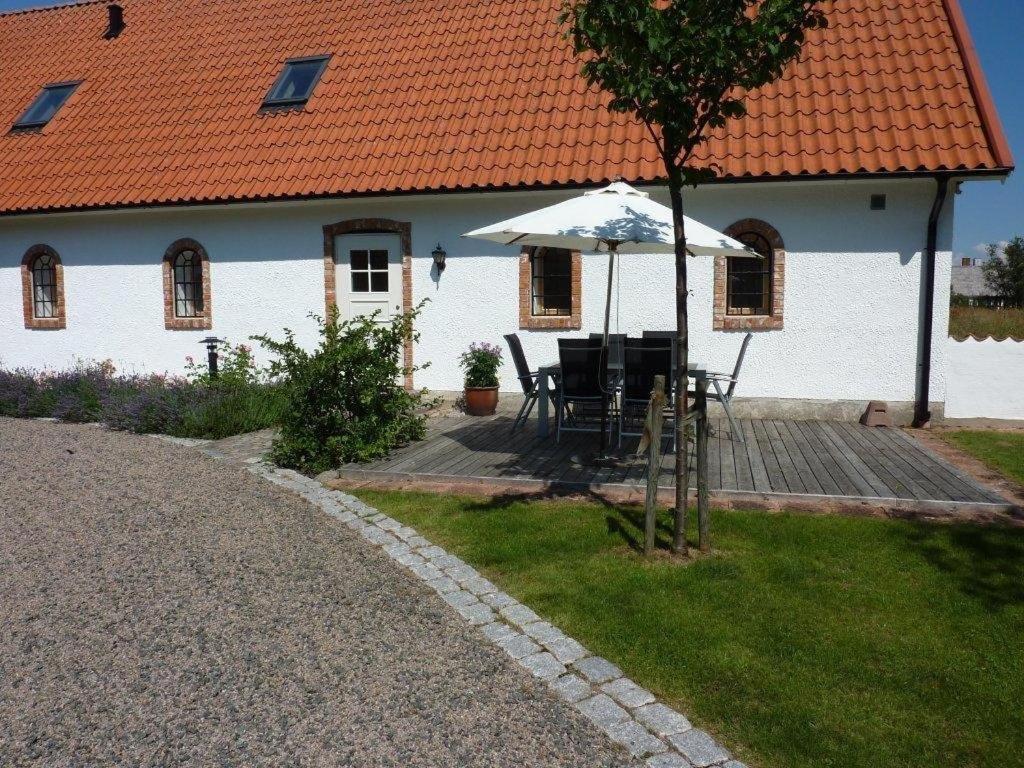ein weißes Haus mit einem Tisch und einem Regenschirm in der Unterkunft Linda Gård apartment in Yngsjö