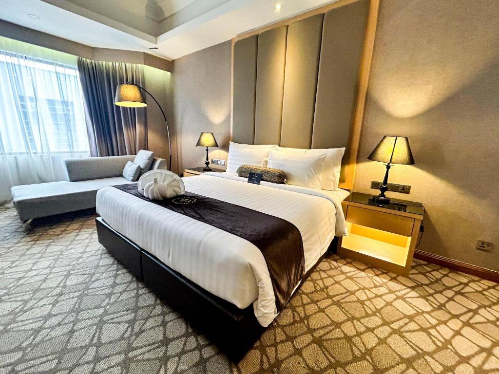 A king room photographed from the foot of the bed, with a sofa and full-height window curtains.