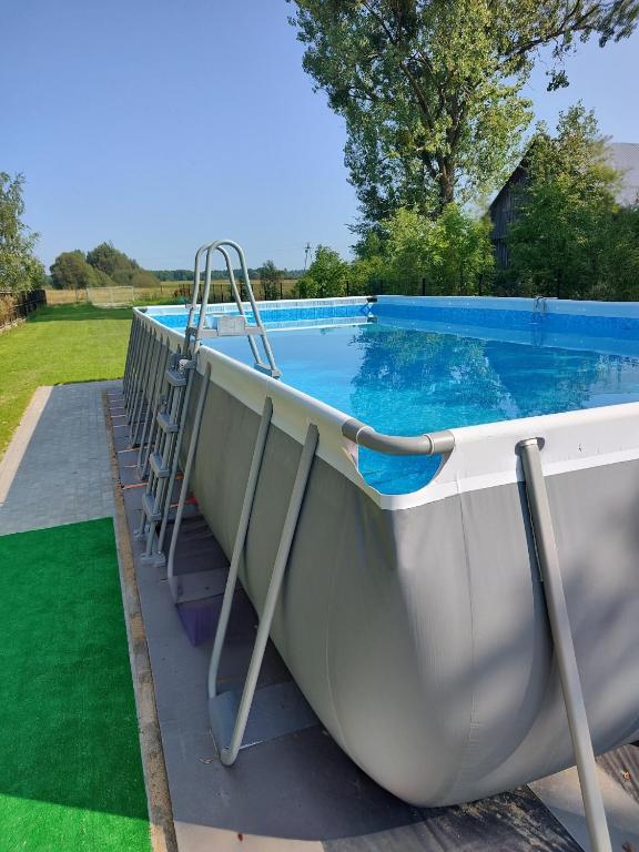 a boat with a ladder next to a swimming pool at Domek z bala na Podlasiu z balią ogrodową in Suszcza