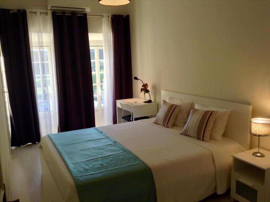 um quarto com uma grande cama branca e janelas em Lisbon Belém Apartment em Lisboa