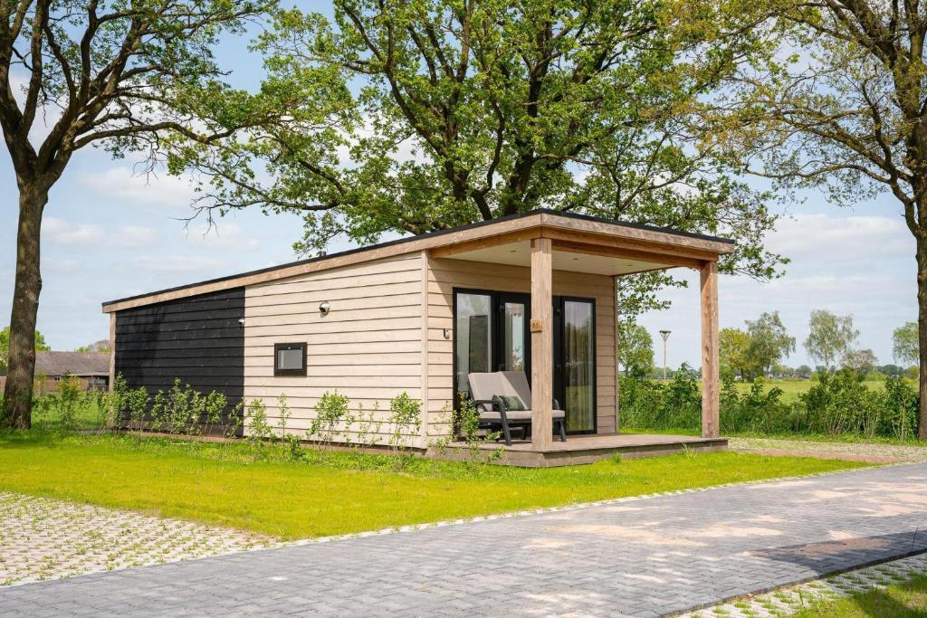 a small cabin in a field with a tree at Panorama Wellness Lodge jacuzzi sauna and sunshower 2 persons copy in Rijssen