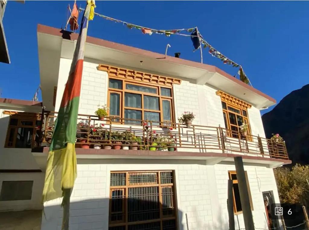 a white house with a balcony and a flag at New Buddha Homestay By StayApart in Tabo