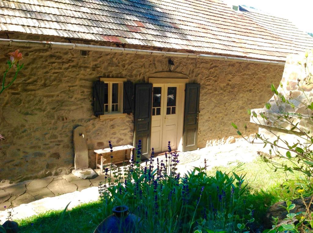 een stenen huis met een witte deur en zwarte luiken bij Kamenná chalupa in Hodruša