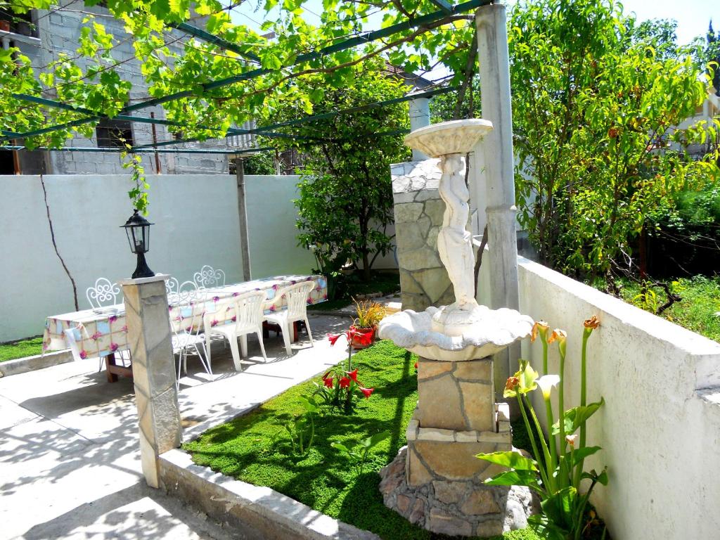 a stone fountain in a garden with a bench at Apartments Marijana in Tivat