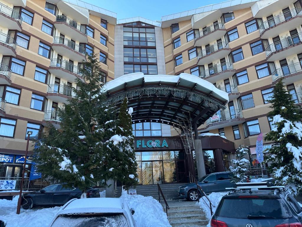 a hotel with cars parked in front of a building at Studio in Hotel Flora Borovets in Borovets