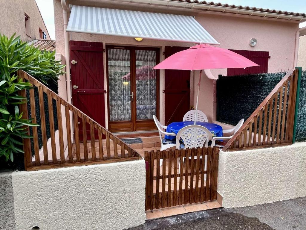 - une table et des chaises avec un parasol rose sur la terrasse couverte dans l'établissement Maison 2 pièces mezzanine 4 couchages ARGELES SUR MER AR210-020, à Argelès-sur-Mer