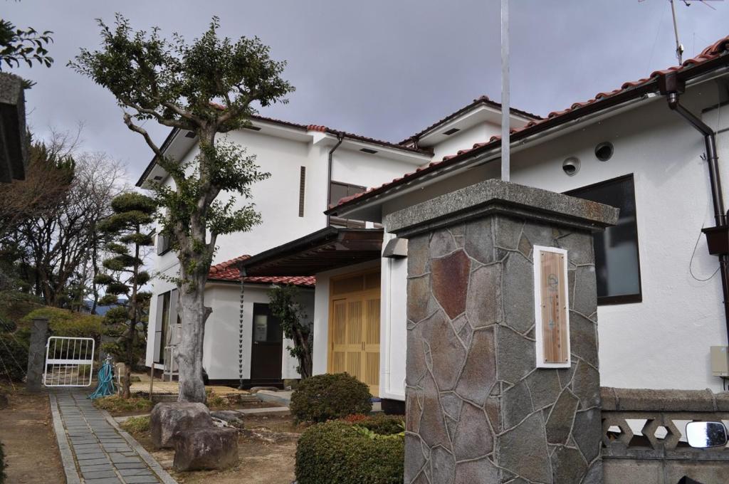 a house with a stone pillar in front of it at 尾道やすらぎの宿しーそー in Onomichi