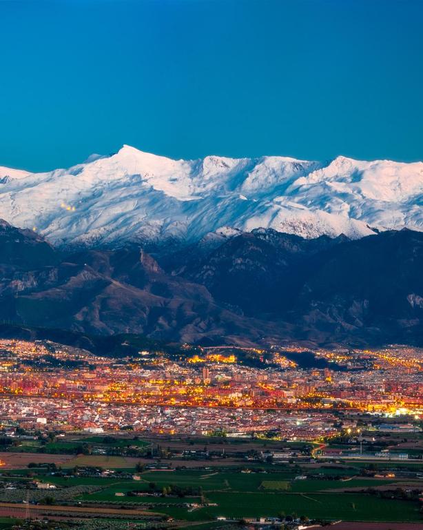 a view of a city with snow covered mountains at Ventana a Granada de Marijose in Las Gabias